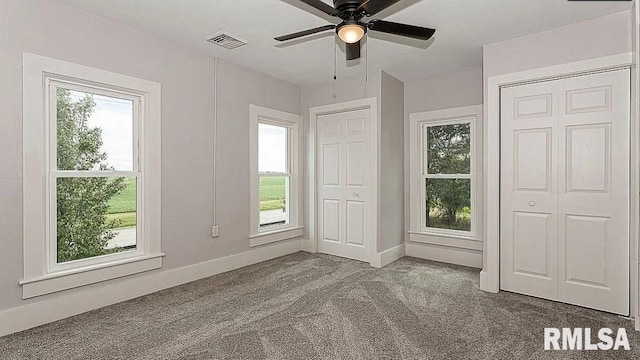 unfurnished bedroom with visible vents, baseboards, multiple windows, and carpet flooring