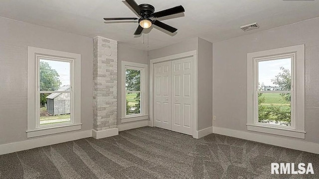 unfurnished bedroom featuring ceiling fan, ornate columns, a closet, and dark colored carpet