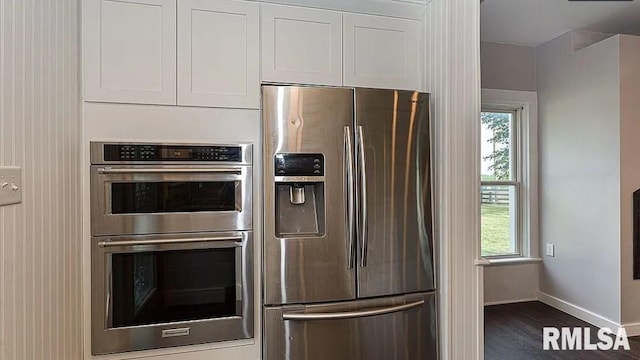 kitchen with stainless steel appliances, white cabinetry, and dark wood-type flooring