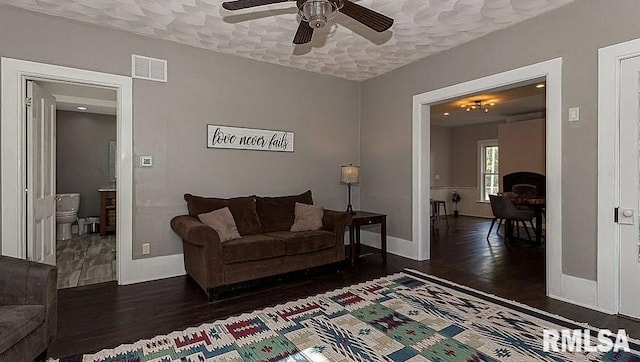 living room featuring ceiling fan, a textured ceiling, and dark hardwood / wood-style floors