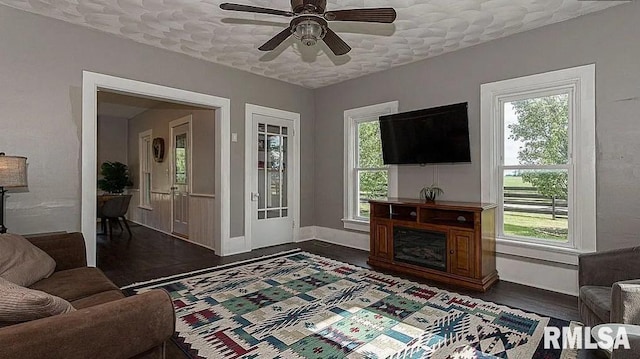 living room with ceiling fan, a textured ceiling, and dark hardwood / wood-style floors