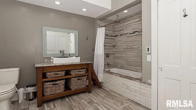 full bathroom featuring vanity, a textured ceiling, wood-type flooring, shower / tub combo with curtain, and toilet