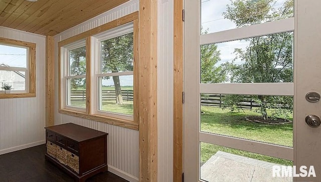 doorway to outside with a healthy amount of sunlight and wood walls