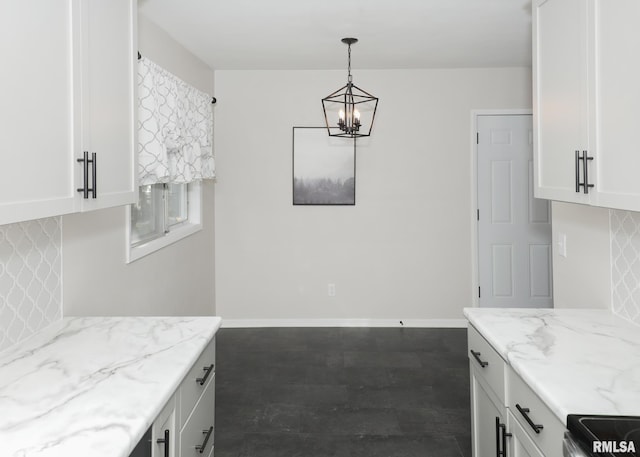 kitchen with light stone counters, white cabinets, and decorative light fixtures