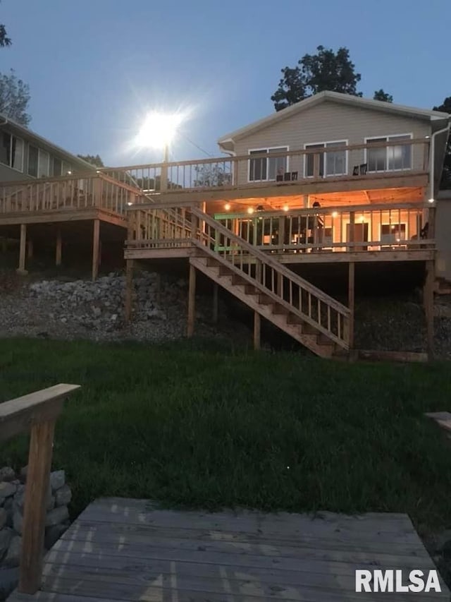 back house at dusk with a deck and a yard