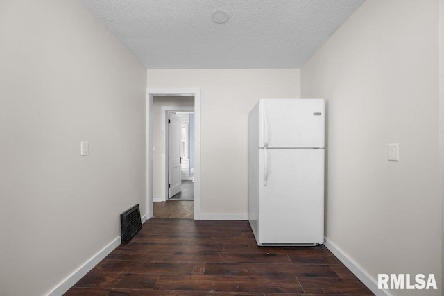 corridor with a textured ceiling and dark hardwood / wood-style floors