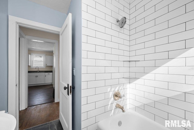 full bathroom with hardwood / wood-style flooring, vanity, tiled shower / bath, and a textured ceiling