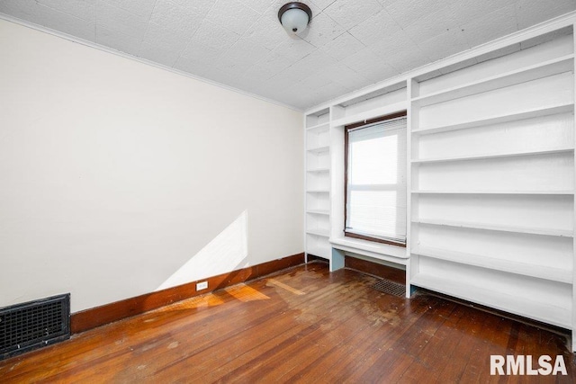 spare room featuring dark hardwood / wood-style floors and built in shelves