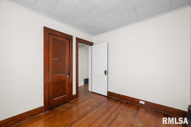 unfurnished room featuring dark hardwood / wood-style floors and crown molding