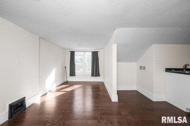 interior space featuring dark wood-type flooring, sink, and a textured ceiling