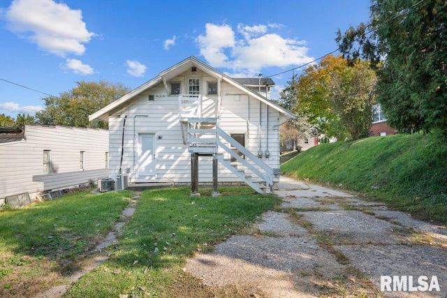 rear view of house featuring cooling unit and a lawn