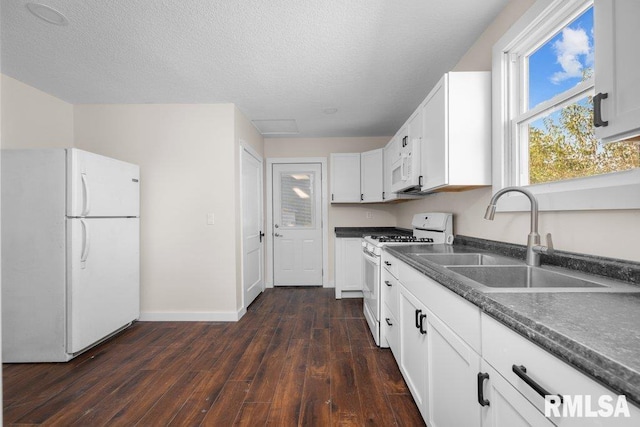 kitchen with white cabinets, dark wood-type flooring, white appliances, sink, and a textured ceiling