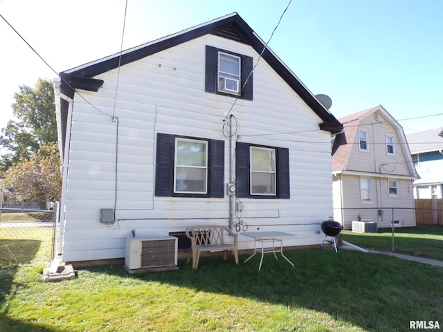 rear view of property featuring a lawn and central air condition unit