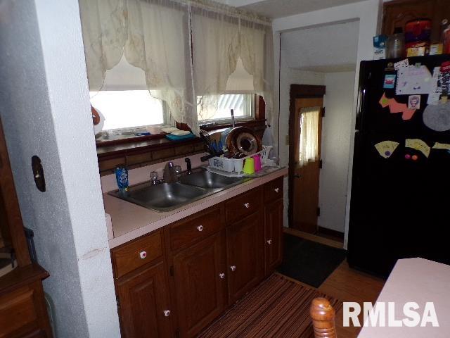 kitchen featuring wood-type flooring, sink, and black refrigerator