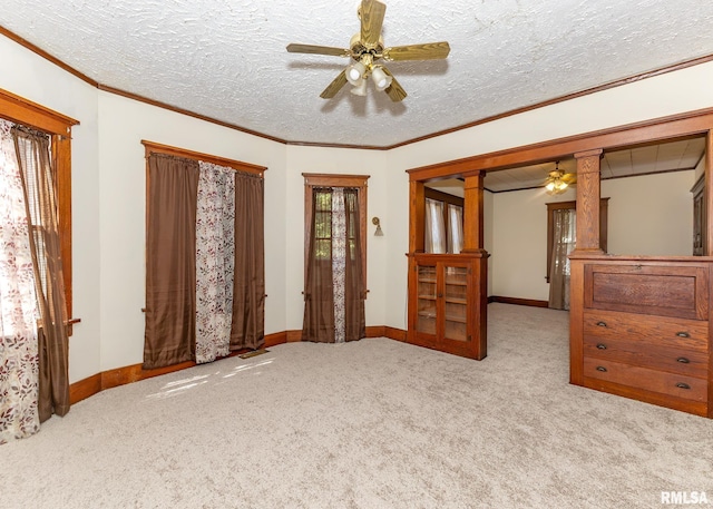 interior space with ceiling fan, a textured ceiling, and ornamental molding