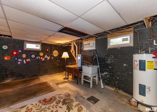 basement featuring water heater, electric panel, and a paneled ceiling