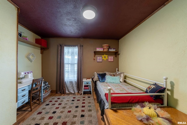 bedroom with ornamental molding, a textured ceiling, and hardwood / wood-style floors