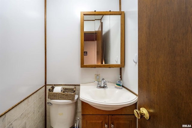 bathroom featuring vanity, tile walls, and toilet