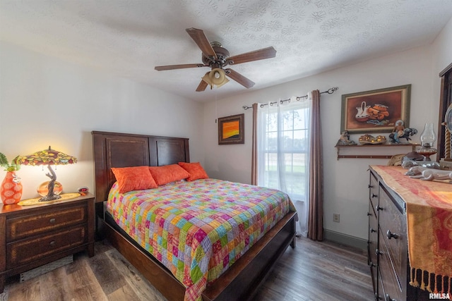 bedroom with a textured ceiling, dark wood-type flooring, and ceiling fan