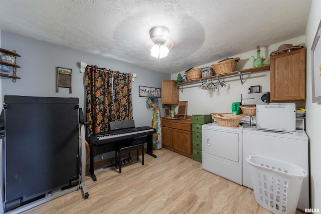 laundry area with ceiling fan, light hardwood / wood-style floors, a textured ceiling, and washer and dryer