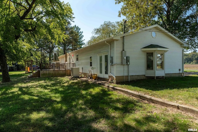 back of house featuring cooling unit, a deck, and a yard