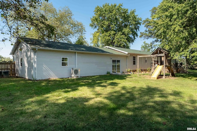 rear view of house with a playground, a yard, and ac unit