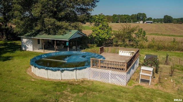 view of swimming pool featuring a lawn, a rural view, and a wooden deck