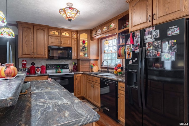 kitchen featuring hanging light fixtures, tasteful backsplash, black appliances, hardwood / wood-style flooring, and sink