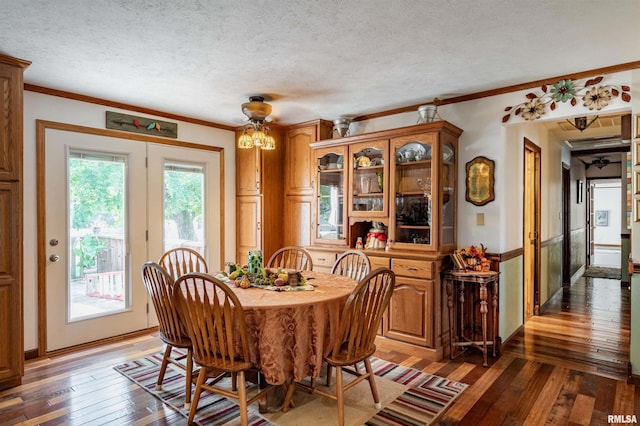 dining room featuring a textured ceiling, crown molding, and dark wood-type flooring