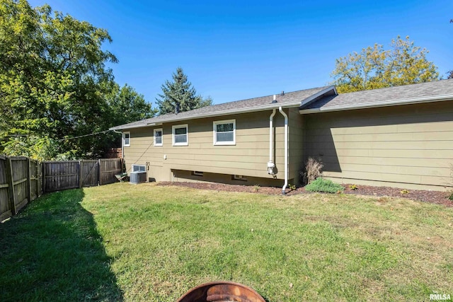 rear view of property featuring a yard and central air condition unit