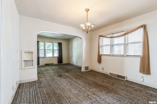 unfurnished room featuring dark colored carpet and a chandelier