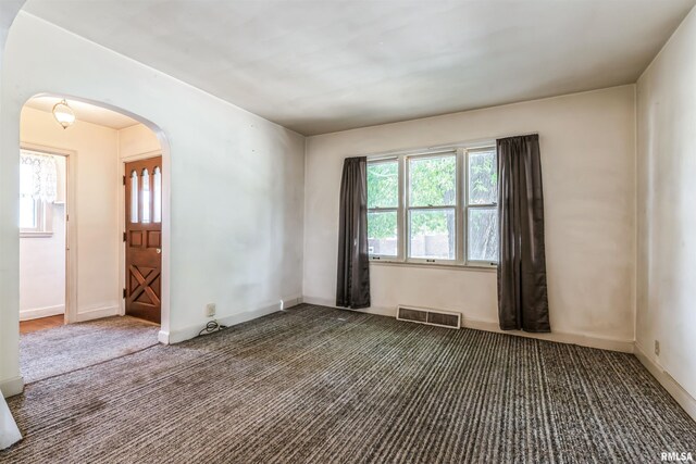 empty room featuring a notable chandelier and dark carpet