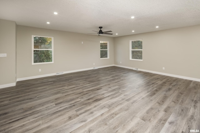 spare room with ceiling fan, a textured ceiling, hardwood / wood-style floors, and a wealth of natural light