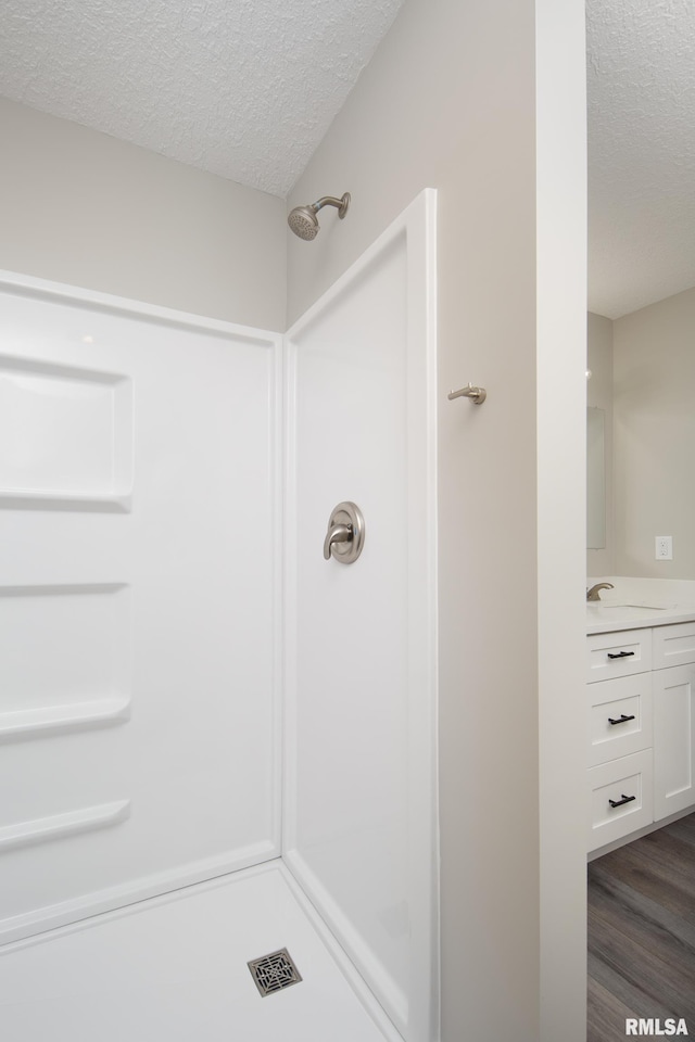 bathroom featuring hardwood / wood-style floors, vanity, walk in shower, and a textured ceiling