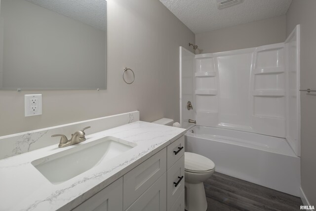 full bathroom featuring toilet, washtub / shower combination, hardwood / wood-style flooring, vanity, and a textured ceiling