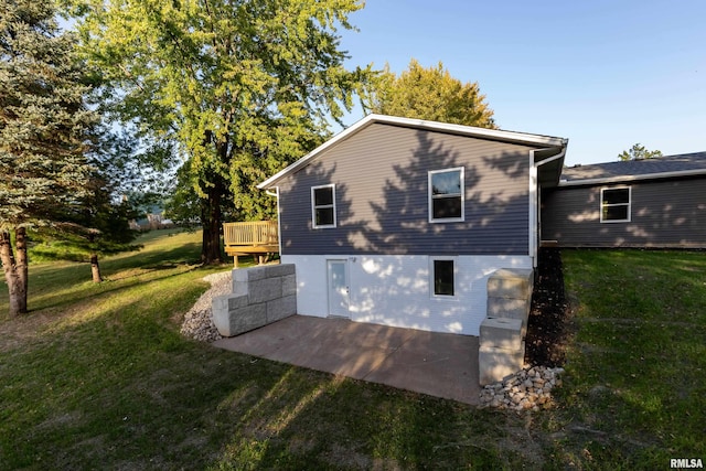 view of property exterior featuring a deck, a patio, and a lawn