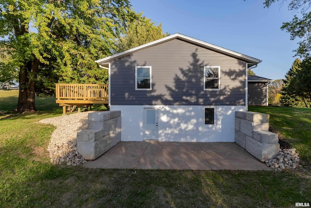 view of side of home featuring a patio, a lawn, and a deck