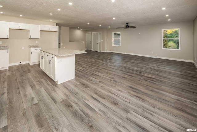 kitchen featuring a kitchen island, light stone countertops, white cabinetry, and light hardwood / wood-style floors