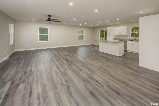 unfurnished living room with hardwood / wood-style flooring, ceiling fan, and a textured ceiling