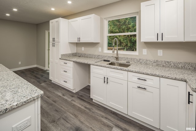 kitchen featuring dark wood-type flooring, white cabinets, sink, and light stone counters