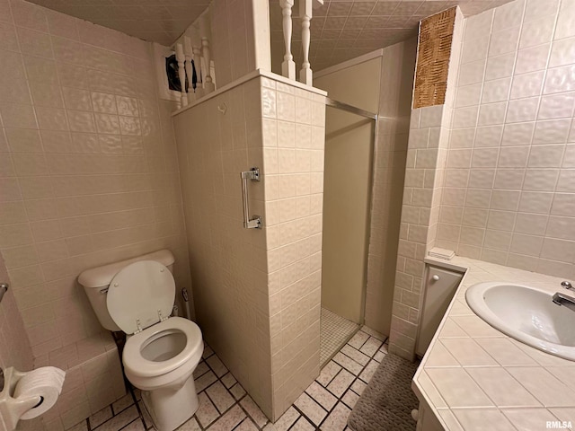 bathroom with vanity, tile walls, toilet, and tiled shower