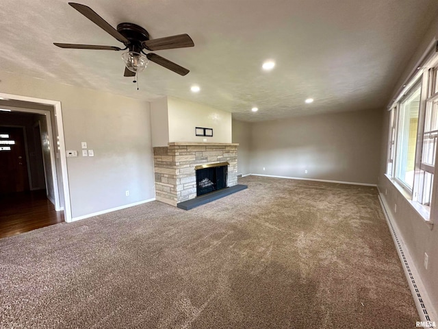 unfurnished living room with ceiling fan, a stone fireplace, a textured ceiling, and carpet flooring