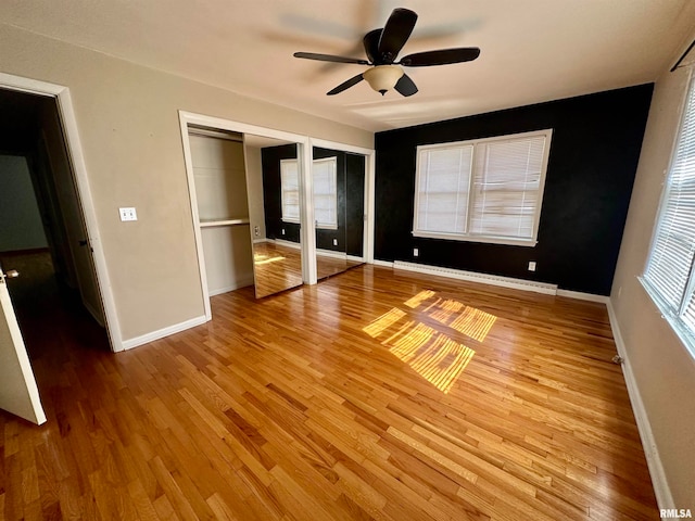 unfurnished bedroom featuring ceiling fan, multiple closets, light hardwood / wood-style floors, and a baseboard heating unit