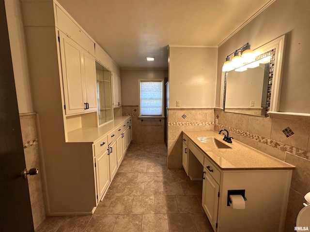 bathroom with crown molding, vanity, and tile walls