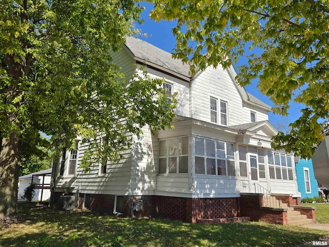 back of property featuring a yard and a sunroom