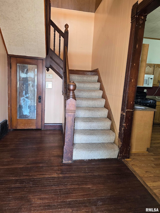 stairs with wooden walls and hardwood / wood-style floors