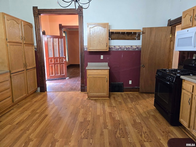 kitchen with wood-type flooring, black gas stove, and an inviting chandelier