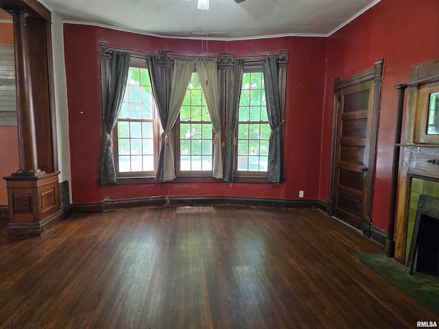 unfurnished dining area featuring crown molding, a tiled fireplace, and dark hardwood / wood-style flooring