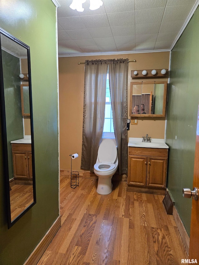 bathroom featuring crown molding, hardwood / wood-style floors, vanity, and toilet