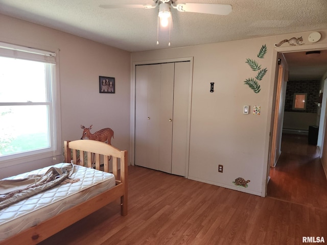 bedroom with ceiling fan, a textured ceiling, a closet, and wood-type flooring